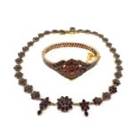 A 19th century gilt metal and garnet bangle and matching necklace, the oval centre piece flanked