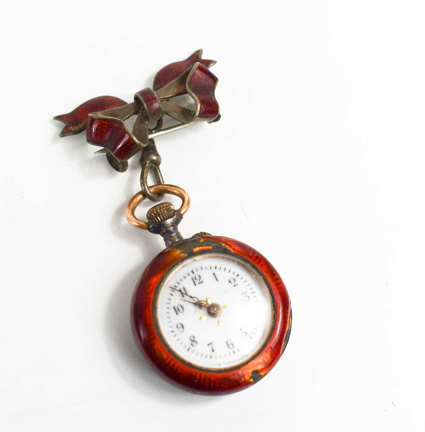 A silver and red enamel ladies pocket watch, with bow form red enamel brooch, gilded fleur-de-lys