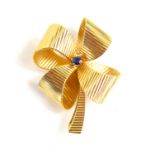 A 14k gold ribbon brooch set with a single sapphire to the centre, 11.2g.