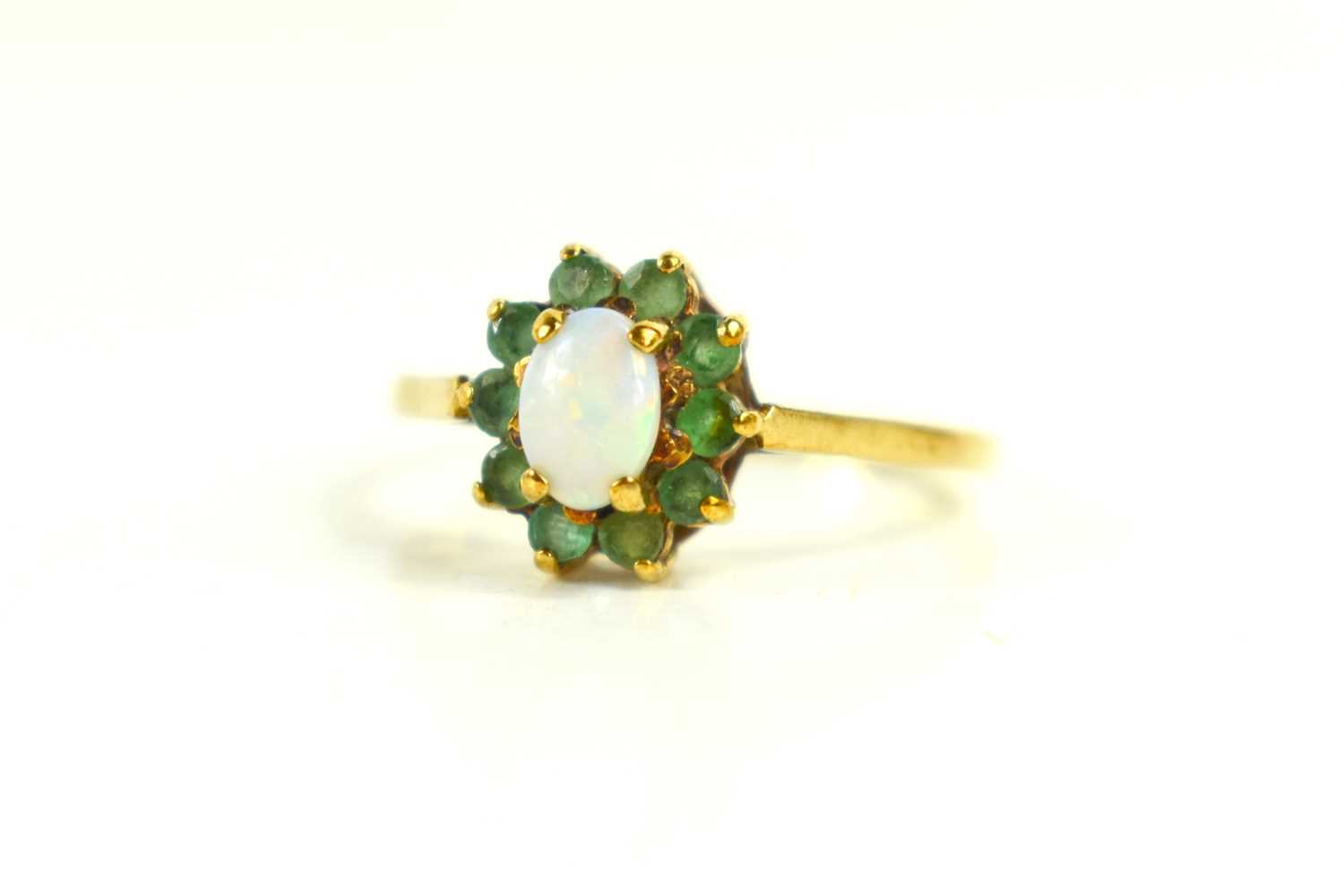 A 9ct gold, opal and emerald ring, of flowerhead form, the oval opal doublet surrounded by ten small