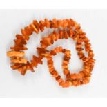An amber necklace, composed of rough cut graduated amber beads, 123g, 90cm long.