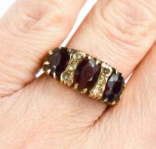 A 9ct gold and garnet three stone ring, each oval cut garnet interspersed with triplet of diamond