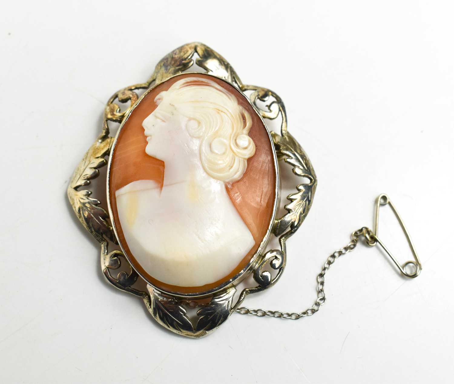 A silver framed cameo, the figure modelled in the modernist style, looking left.