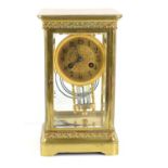 An antique J.E Caldwell & Co mantle clock, the clock suspended in a gilded brass and glass case,