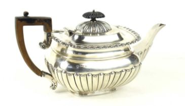 A silver teapot with gadrooned belly and rectangular form ebonised handle and finial, hallmarked for