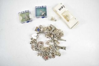 A silver charm bracelet set with thirty five charms 3.53toz, and four further loose charms, boxed.