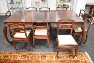 A Chinese hardwood extending dining table with a set of matching dining chairs with cream