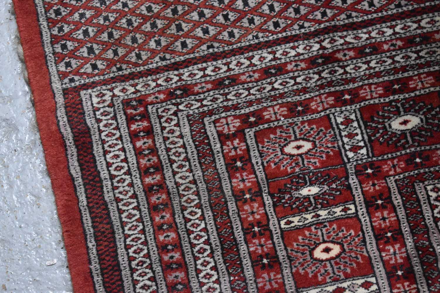 A large wool rug, red ground, with geometric stylised borders and central panel, 285cm by 360cm. - Image 6 of 7