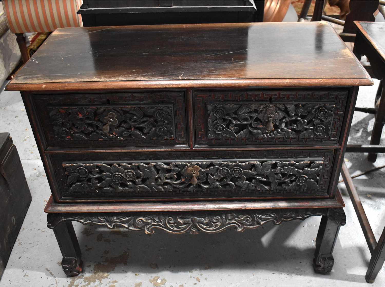 A 19th century Chinese hardwood cabinet on stand, the two over one long drawer carved with