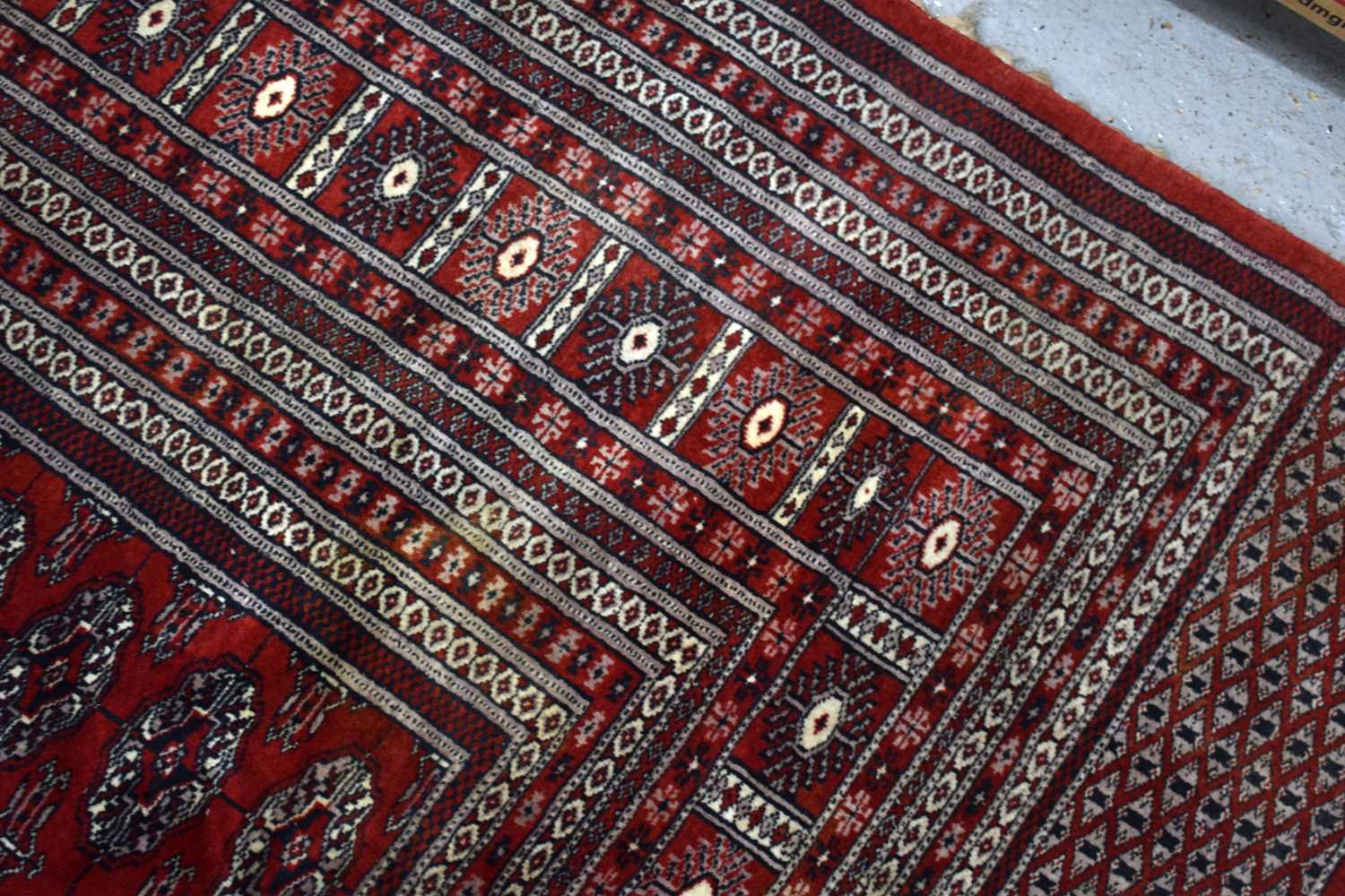 A large wool rug, red ground, with geometric stylised borders and central panel, 285cm by 360cm. - Image 4 of 7