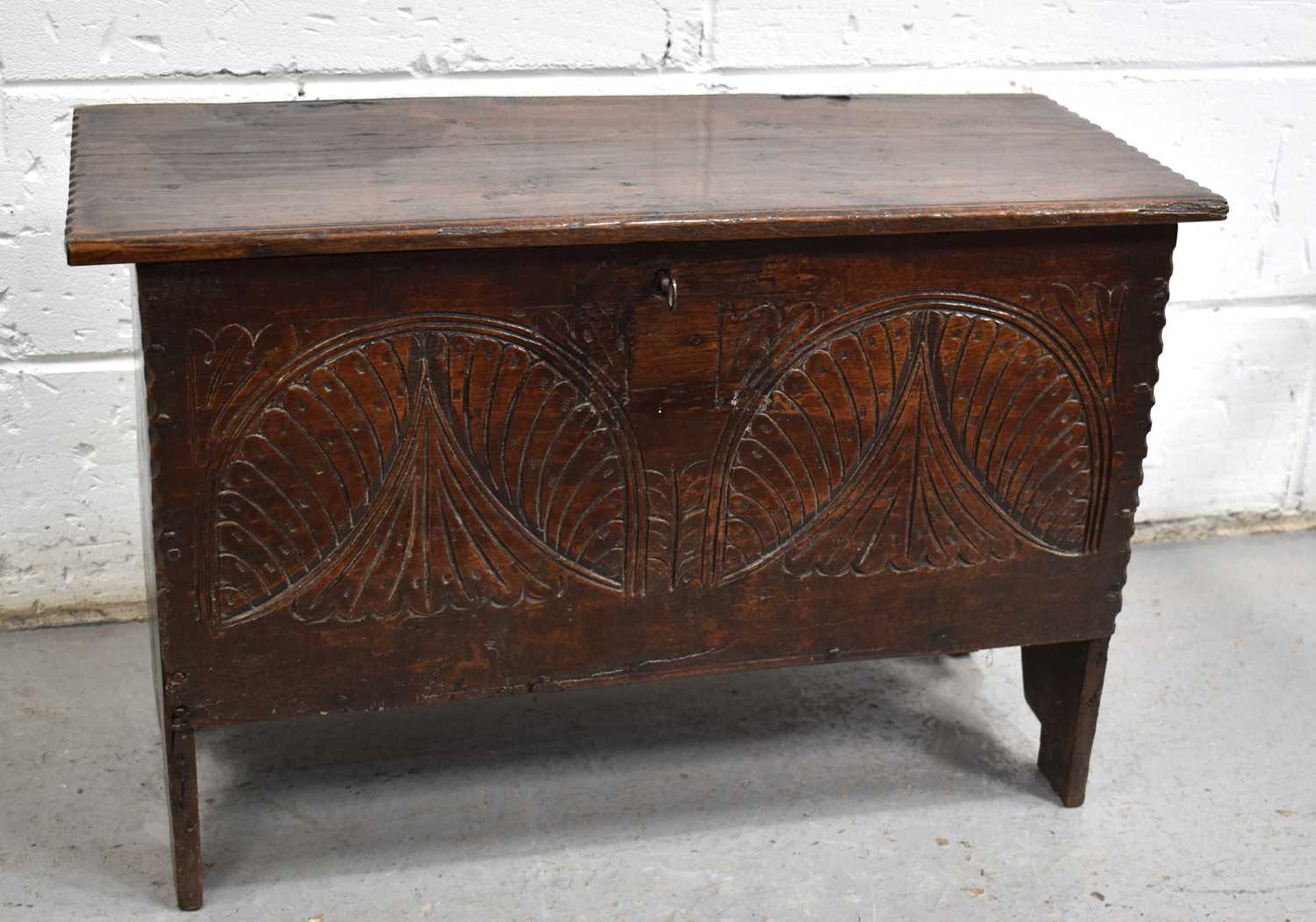 A small 17th century oak coffer, the planked top above a lunette carved front panel and V cut end