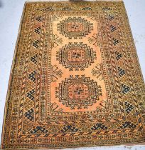 A wool rug, the ochre ground with black, olive and orange decoration, with three lozenges to the