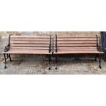 A pair of cast iron benches, painted black with new slats, the cast iron ends of decorative