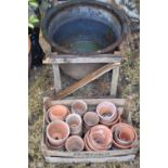 A cast iron bell shaped pot, together with a group of terracotta and garden plant pots.