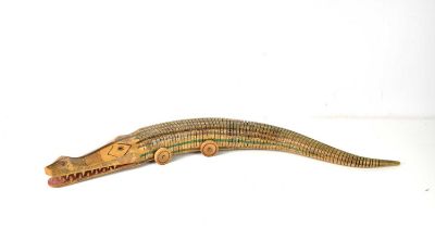 A large hand painted, reticulated, wooden crocodile on wheels, 80cm long.