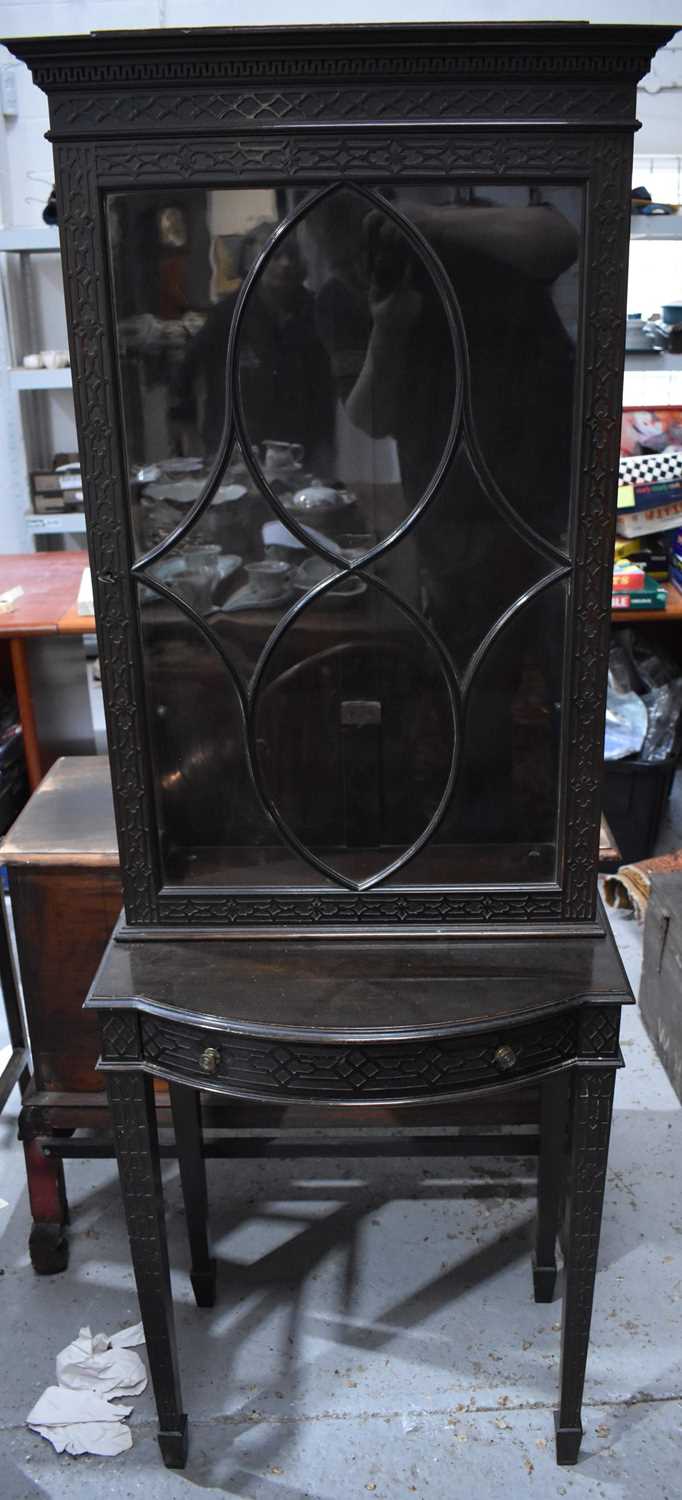 An Edwardian glazed display cabinet on stand, with blind fret carving decorating the borders, drawer