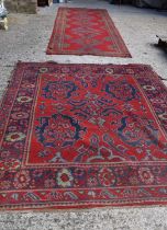 Two antique wool rugs likely Middle Eastern origin both with red ground and stylised motifs and