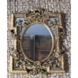 A giltwood style wall mirror, with central oval frame and pierced floral reserves to the shaped