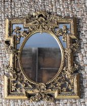 A giltwood style wall mirror, with central oval frame and pierced floral reserves to the shaped