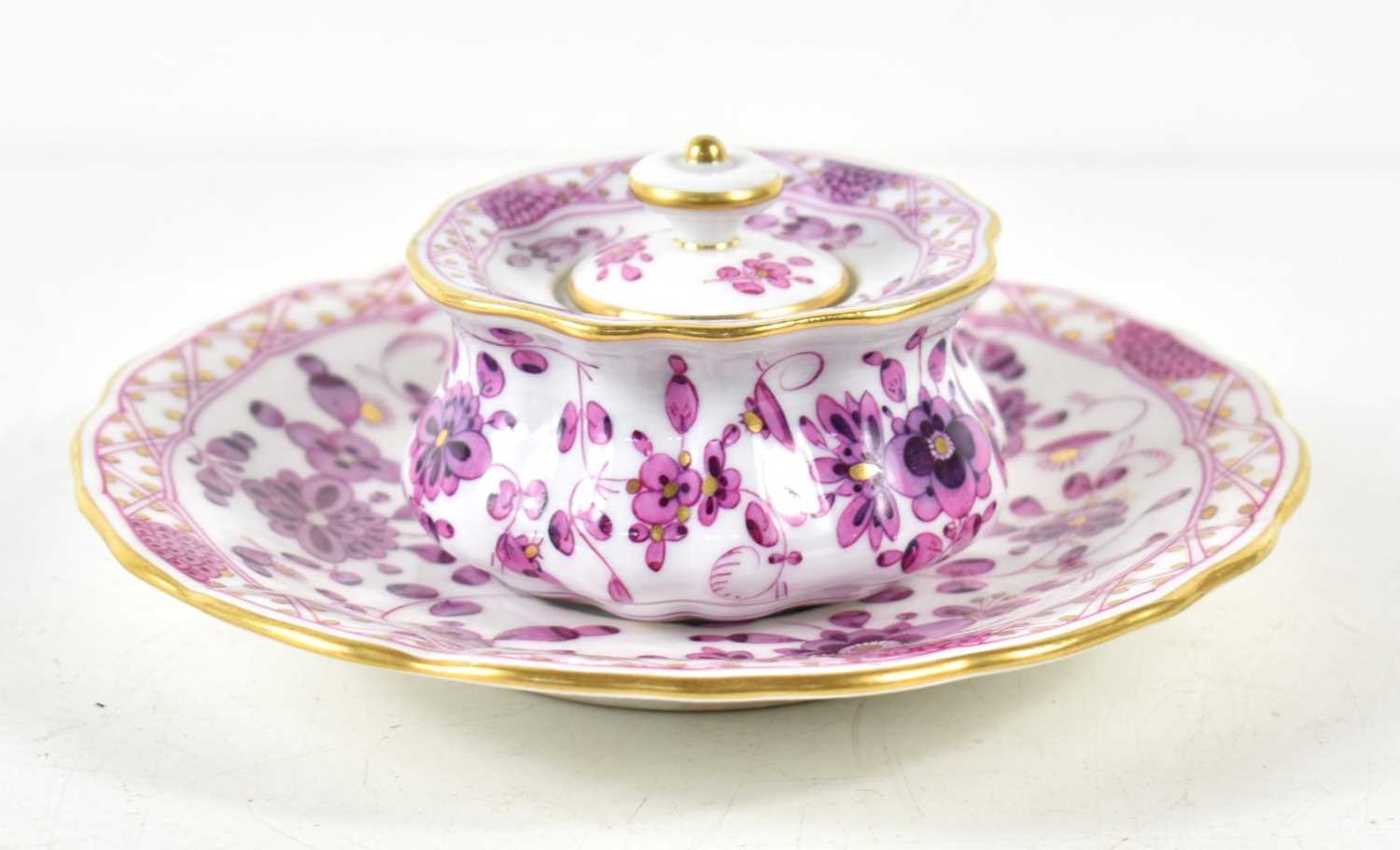 A Meissen lidded pot and saucer, decorated in a detailed purple floral pattern with gilding to the