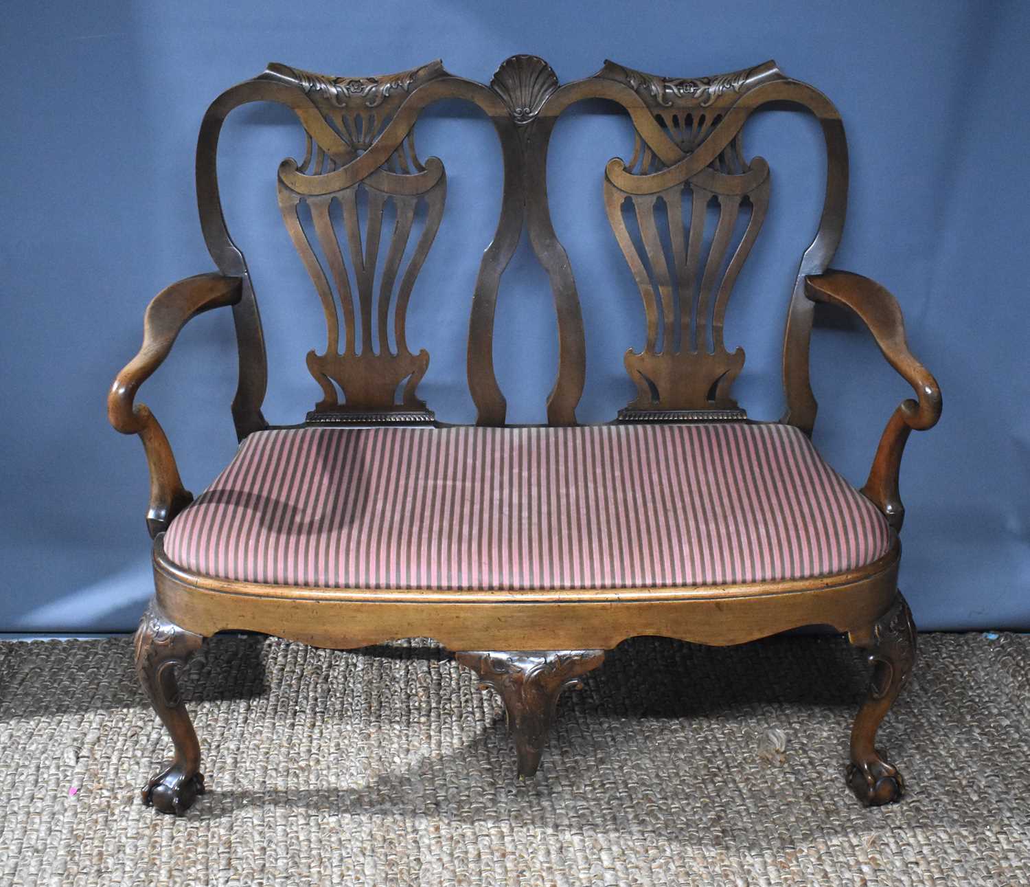 A Queen Anne style settee, with walnut double back, pierced and carved splats, shepherds crook arms,