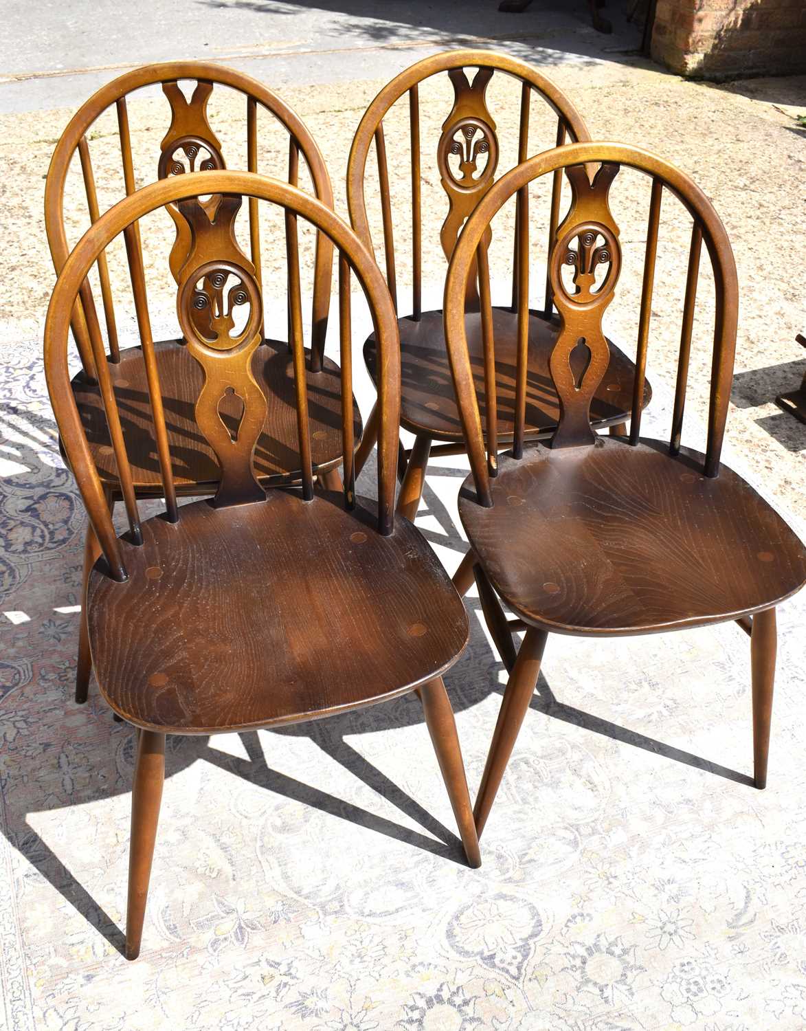 Four Ercol dining chairs with pierced back splats, H form stretchers.