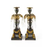 A pair of Empire gilt bronze candlesticks, the candle socket above a pierced and gilded leaf form