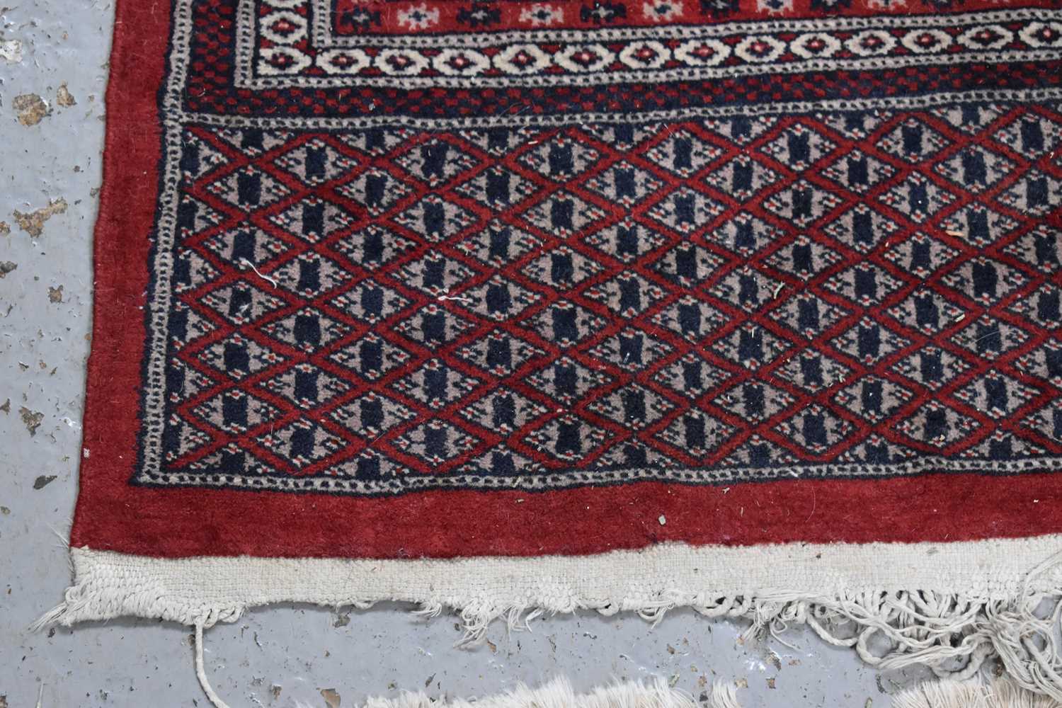 A large wool rug, red ground, with geometric stylised borders and central panel, 285cm by 360cm. - Image 5 of 7