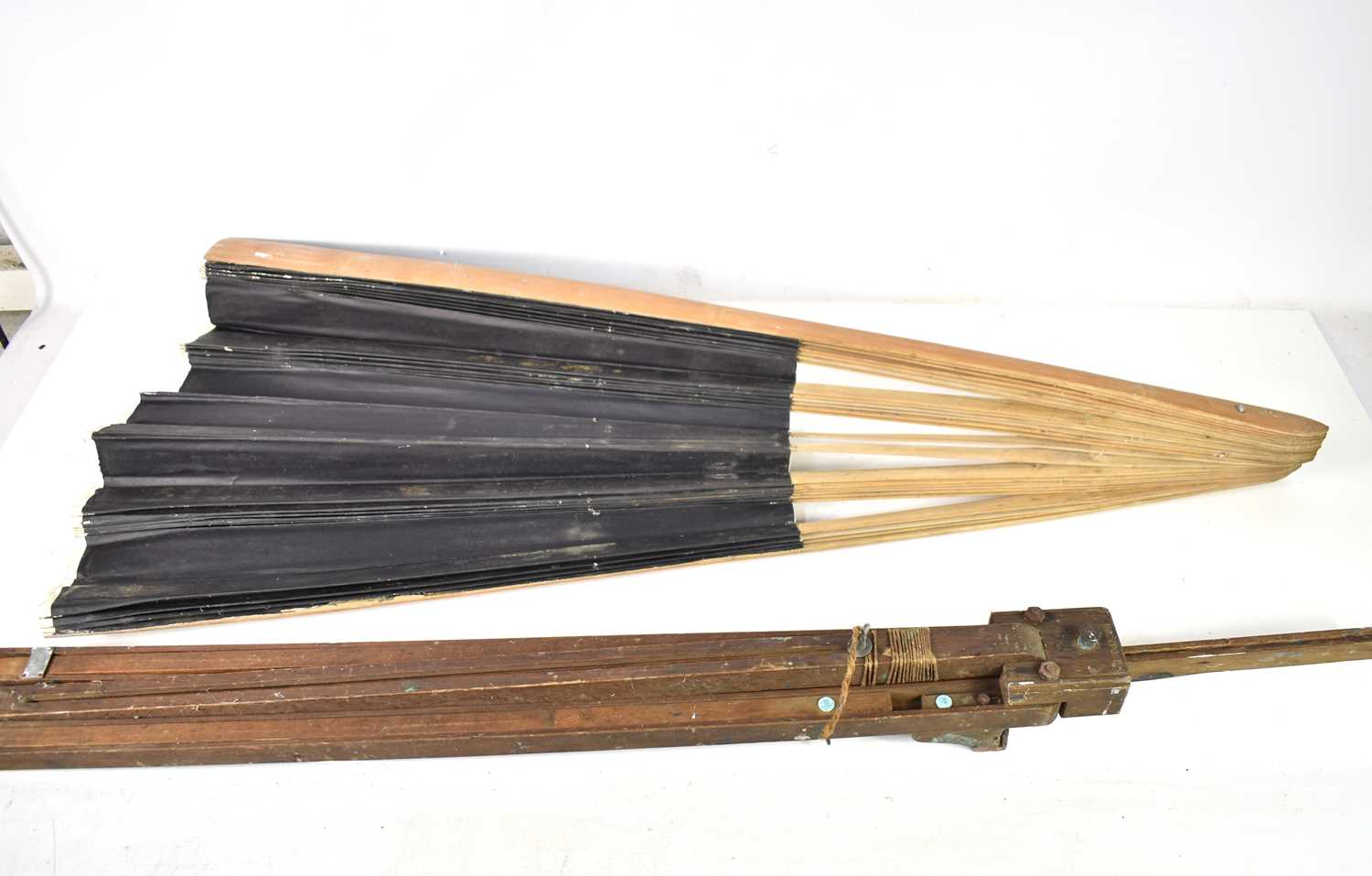 A vintage folding easel and an oversized fan, with black painted leaf and bamboo sticks and
