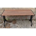 A cast iron and wooden garden table with new slats, the ends having scrollwork, 65cms tall by 139cms