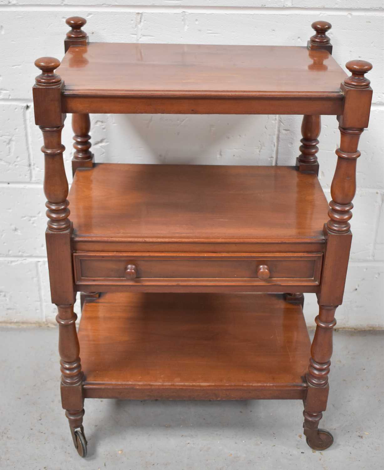 A Victorian mahogany three tiered buffet, the central tier with drawer, the whole with turned