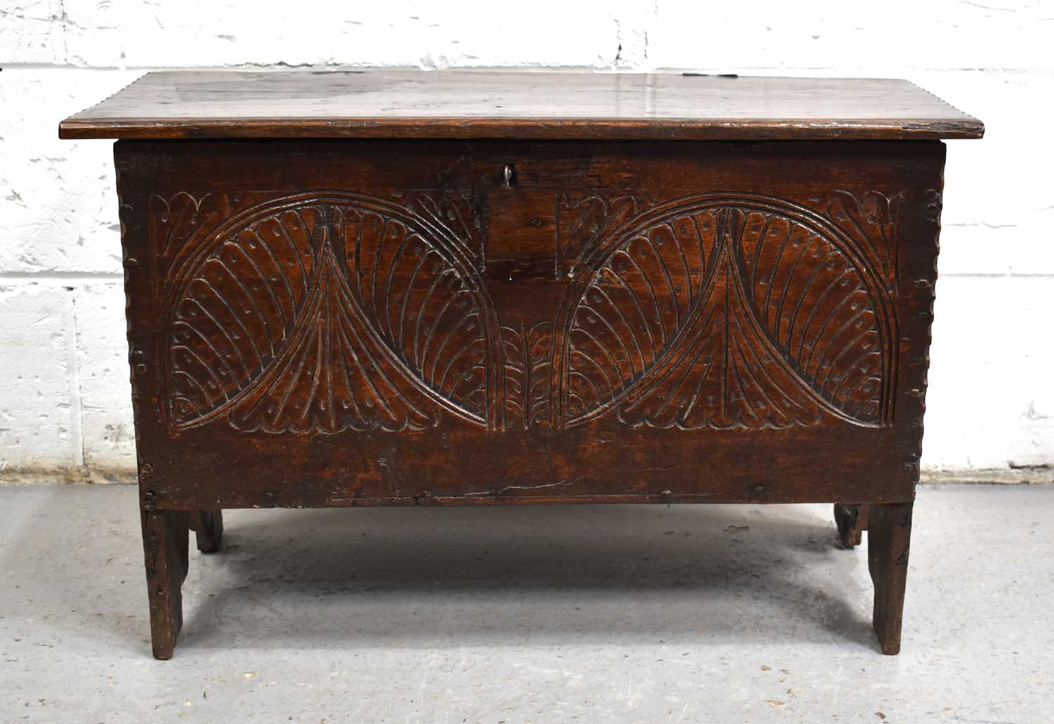 A small 17th century oak coffer, the planked top above a lunette carved front panel and V cut end - Image 2 of 2