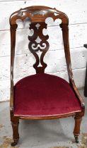 A 19th century Victorian rosewood and mahogany nursing chair with decorative pierced splat and top