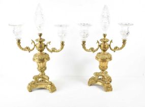 A pair of gilt bronze and glass candelabra, each with two glass candleholders and central final,