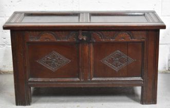 A 17th century oak coffer with two panel lid and front, the lunette carved top rail housing lock