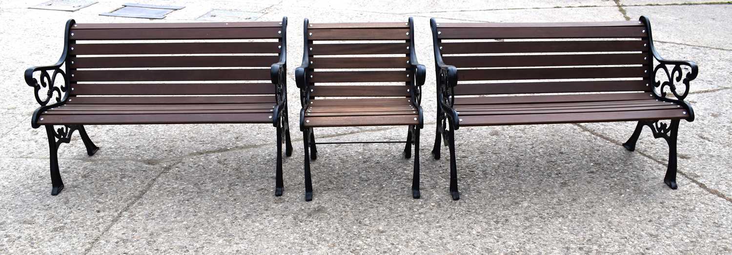 A pair of cast iron garden benches, with later mahogany slats, the cast iron ends of decorative