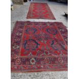 Two antique wool rugs likely Middle Eastern origin both with red ground and stylised motifs and