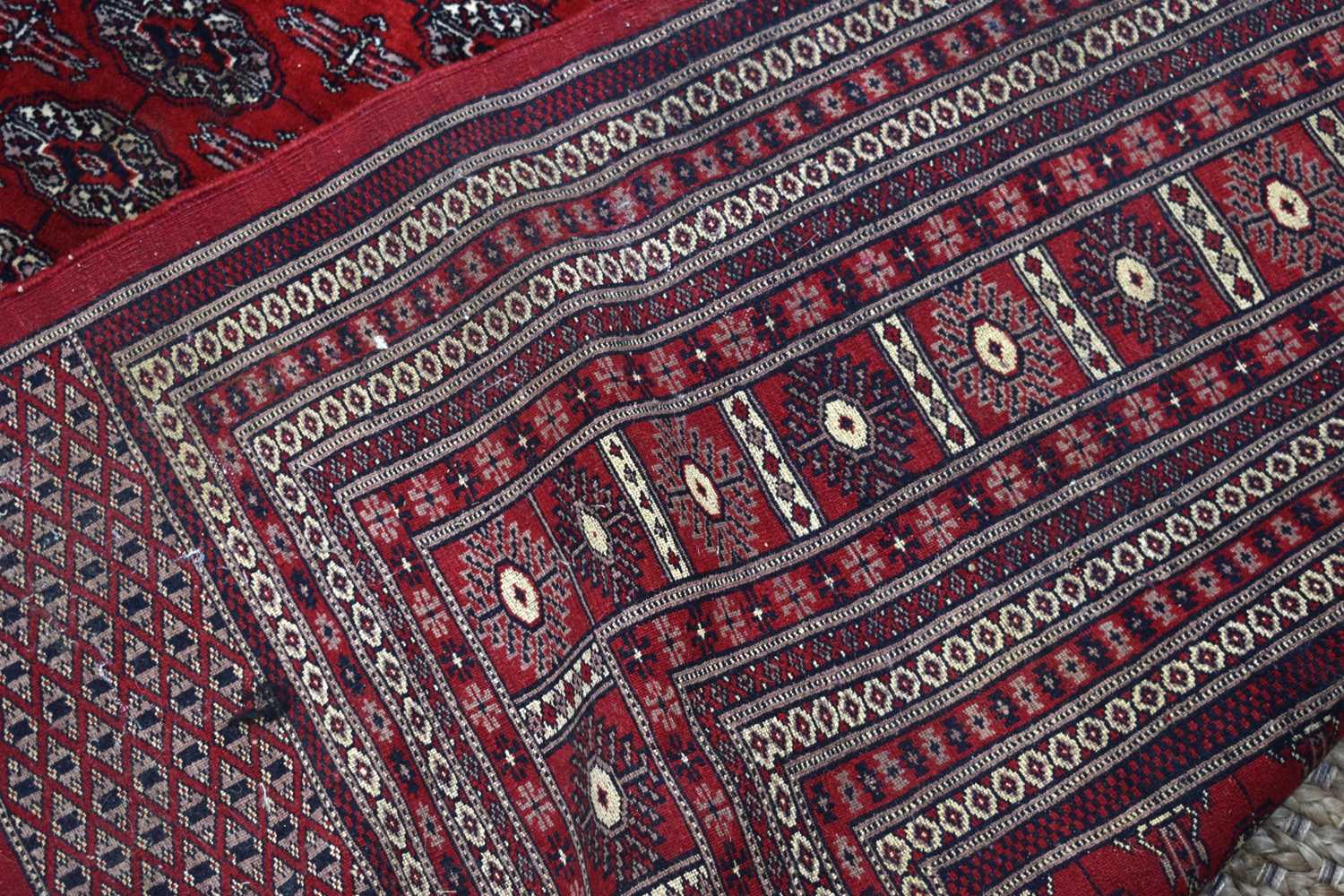 A large wool rug, red ground, with geometric stylised borders and central panel, 285cm by 360cm. - Image 2 of 7