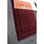 A Middle eastern red ground rug decorated with stylised floral motifs and stylised borders and