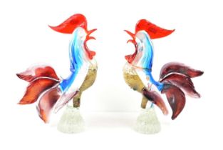 A pair of Murano glass cockerels in red, white and blue glass with speckled breasts on a clear glass