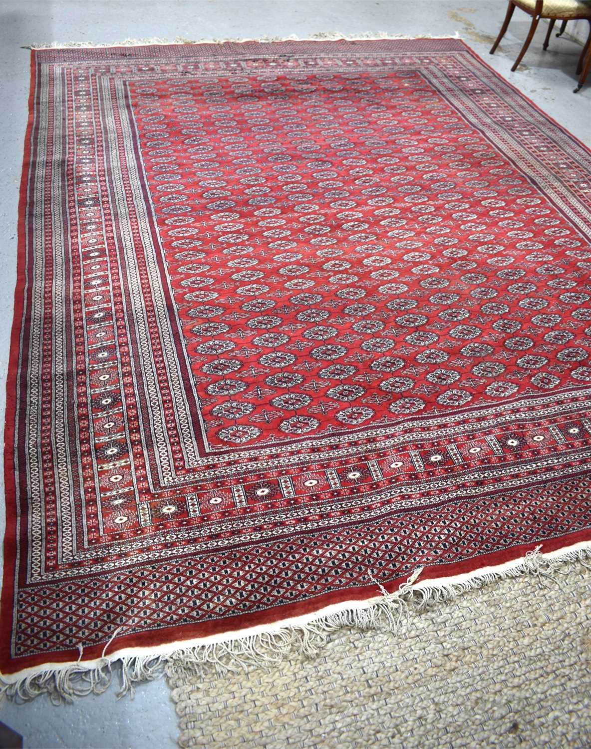 A large wool rug, red ground, with geometric stylised borders and central panel, 285cm by 360cm. - Image 3 of 7