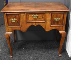 An 18th century walnut lowboy, the apron front housing three drawers raised on cabriole legs with