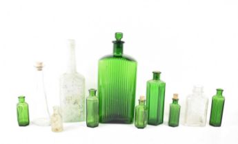 A group of green and clear apothecary and similar bottles, including a large rectangular example