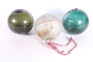 Two green glass fishing floats and a metal float. (3)