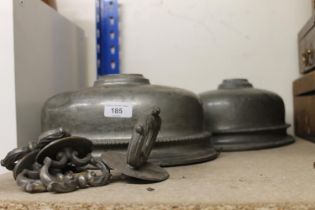 Two white metal meat covers and a cast metal table clock.