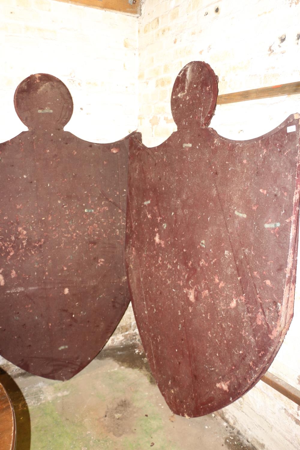 Four large shield shaped panels, previously used for displaying arms including swords, covered in