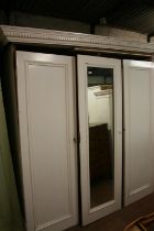 Antique cream painted three door wardrobe, the dentil work cornice above central mirror panel