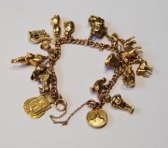 Gold curb bracelet with various charms, mostly 9ct, 58.8g gross.