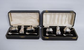 Two silver three-piece condiment sets with spoons and blue glass liners, hallmarks for Birmingham,