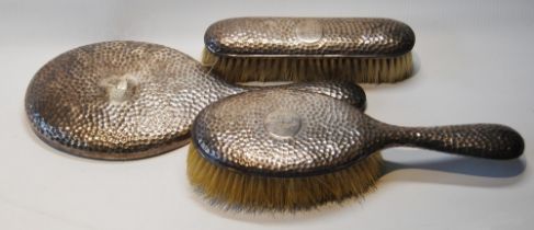 Pair of hammered silver hair brushes and mirror matching the preceding lot.